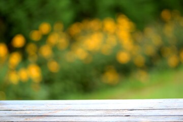 Blue old wooden table and green with yellow flowers bokeh background with a space for text, design elements or product presentation, softly blurred background and selective focus. Empty space.