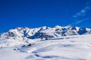 Winter landscape with mountains covered with snow under a blue sky during the day