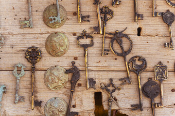 A collection of old and rusted keys are hanging on a wooden wall