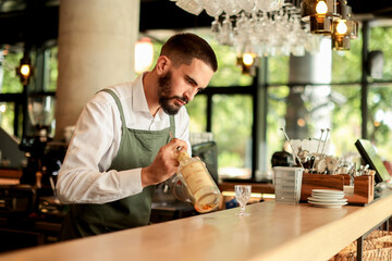 Talented bartender skillfully prepares a cocktail at a stylish urban bar on a sunny afternoon, showcasing artistry and precision in mixology