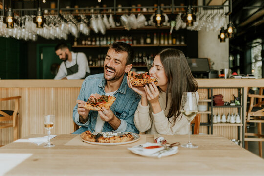 Enjoying delicious pizza together at a cozy restaurant with friends during a lively evening gathering