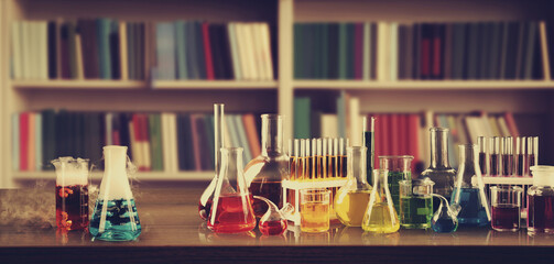 Chemist's cabinet with laboratory glassware and shelves full of books, vintage style. Banner design