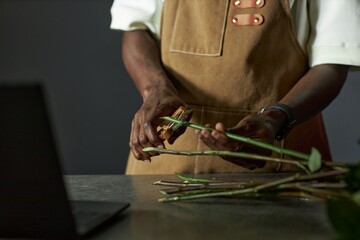 Minimal closeup of male florist arranging bouquet and cutting flower stems in low lighting copy space