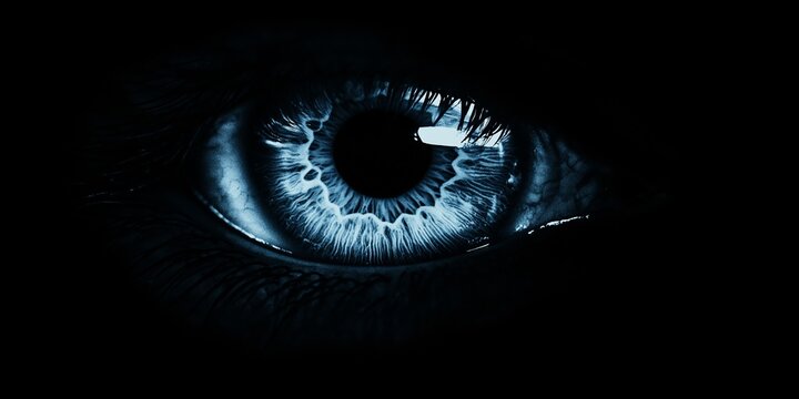 A close up of a blue eye with a dark background. The eye is the main focus of the image, and the blue color gives it a calming and serene appearance. The dark background adds a sense of mystery