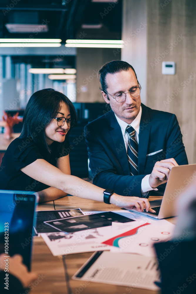 Poster successful multicultural woman and man skilled economists collaborating on project using laptop comp