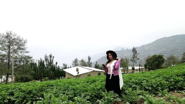 Video de una feliz y bonita campesina con un sombrero hablando por un tel&eacute;fono celular en los Andes peruanos. Mujer usando tel&eacute;fono m&oacute;vil