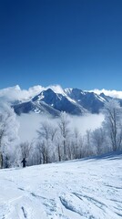 A snow-covered mountain range under a clear blue sky, with white clouds swirling around the peaks.