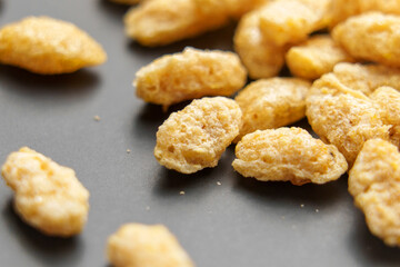 Macro shot of whole grains of processed oat corn flakes on a neutral grey ceramic