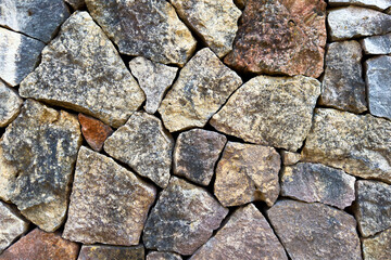 Rough grainy surface of wall stones. Background texture with brown and blue hues outdoors