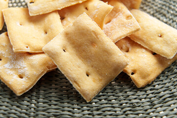 Freshly baked wheat crisp crackers on braided textured kitchen cloth. Macro shot