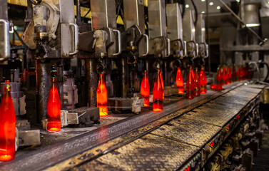 Glass factory, production of glass containers. Molten glass is blown into molds. Robotics in industry. Modern technologies, robotic machines produce products. Technological work at the plant.