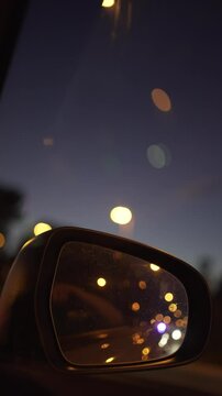 vertical video of car rear-view mirror. Driving and driving at night on the road with lights out of focus.
