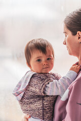 Single mother holding her child. They are looking through the window