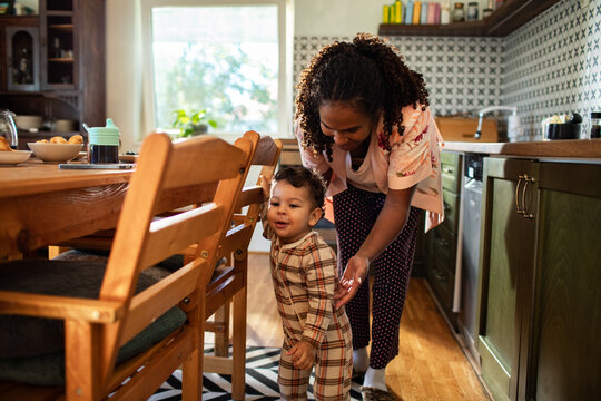 Mother playing with toddler in the kitchen during morning