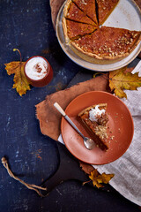 pumpkin pie on a dark background on a terra cotta plate. Top view