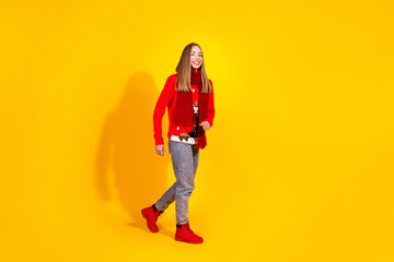 Full body portrait of nice young girl walk empty space wear festive new year sweater isolated on yellow color background