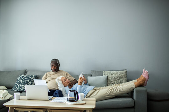 Diverse senior couple reading bills on the couch at home