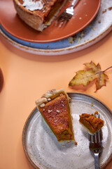 Homemade pumpkin spice pie for the Thanksgiving holiday. Top view with peach background