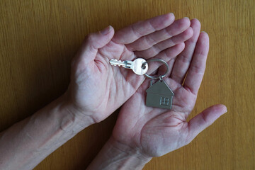 open hands with key and key ring of a house