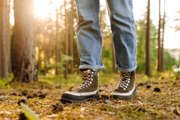 Hiker's boots stepping on a blanket of fallen autumnal orange leaves in the forest. Travel, Hikking.