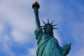 Fototapeta premium Frontales Close Up Portrait vom mit einer Krone besetzten Kopf der Freiheitsstatue in New York, die vor klarem blauen Himmel die Fackel der Freiheit hochhält 
