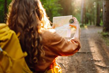 Traveler young woman searching direction with a compass on background of map in the forest....