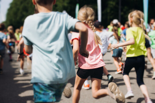 Children marathon runners crowd, young teen sportsmen participants start running in the city streets, crowd of kids joggers in motion, kid group athletes outdoor run, family competition in summer day