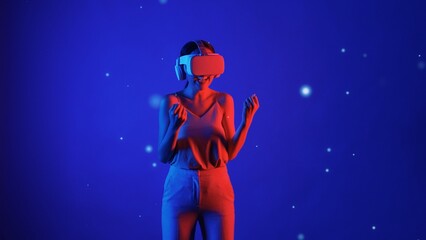 Naklejka premium Woman player using VR glasses transfer to fantastic metaverse game to fist up to be winning fantasy gaming space with lighting bokeh blue smoke meta 3D cyberspace technology meta world. Hallucination.