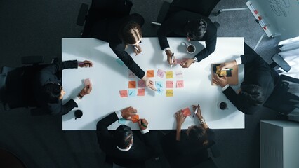 Top down aerial view of diverse business people writing marketing idea or taking a note on sticky notes. Professional executive manager group brainstorm financial plan at meeting room. Directorate.