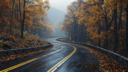 Fototapeta premium The winding road in the mountains is surrounded by autumn trees, with stone guardrails and yellow lines on both sides