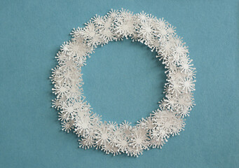 A circle of paper snowflakes on a blue background.. Christmas wreath made of paper snowflakes. Christmas background cut out from paper.
