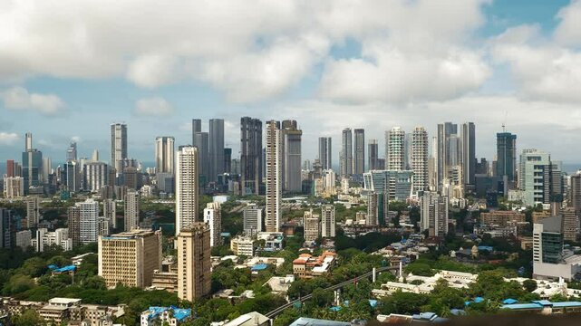 Timelapse view of the vast Mumbai city skyline during the daytime monsoon. The downtown core features a layered panorama of office buildings, condominiums, and modern urban architecture