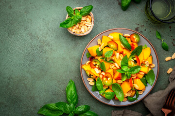 Foodie food salad with peach, hot chili peppers, peanuts and basil, green background, top view