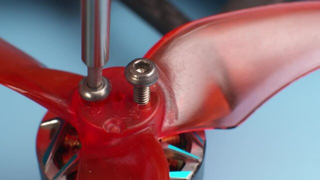 Close-up macro of unscrewing screws securing propellers to brushless motor of self-assembled drone