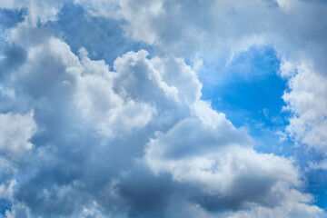 Breakthrough of blue sky with bright light in cumulus clouds