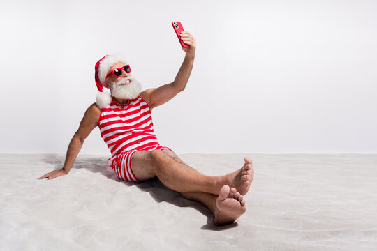 Photo of positive man wear red swimsuit making video video summer season isolated on white sandy beach background