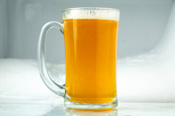 a glass of beer with foam on top. snow ice background in freezer
