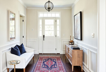 Bright home foyer interior design with white wainscotting sofa rug and console table