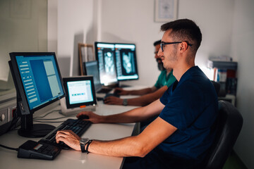 Radiologist analyzing scan results on three computer monitors.