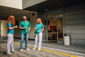 Healthcare professionals enjoying a coffee break, bonding outside facility.