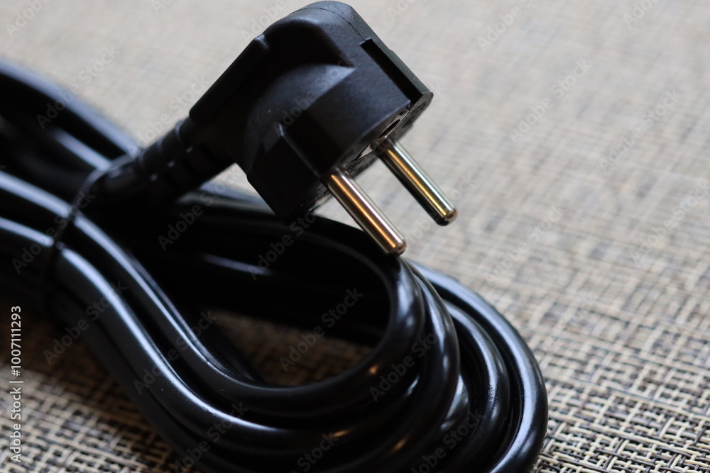 Poster a close-up shot of a black power cord lying on a table.