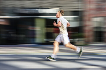 Young man in bright sportswear running on the street in the city, motion blur, panning photography...