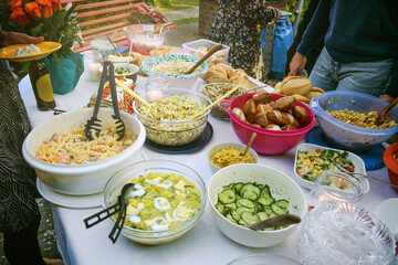 Various homemade salads on a table at an outdoor bring-along party with friends or family, cold buffet at a casual event, selected focus