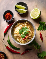 Image of A bowl of ramen noodles with broth, topped with cilantro and chili peppers, served with lime wedges printed on Printed Glass Splashbacks