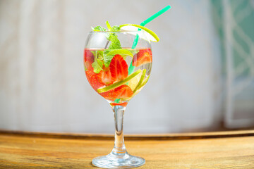 berry cocktail in a glass with a straw raspberries blueberries lemon and mint on the table