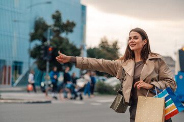 Stylish woman hailing a cab after shopping spree