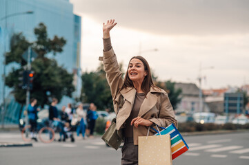 Elegant woman hailing a taxi after shopping spree