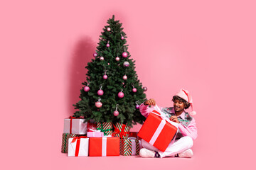 Full length photo of attractive funny guy wear print vest headwear open present celebrating xmas emtpy space isolated pink color background