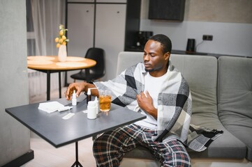 Fototapeta premium rhinitis, medicine and healthcare concept sick african american man in blanket using nasal spray at home