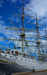żaglowiec z masztami i olinowaniem, żaglowiec w porcie na tle niebieskiego nieba, Ship Mast and Ropes, ship moored in harbor of coastal town, sailing ship with rigging, Sailing ships moored in harbor